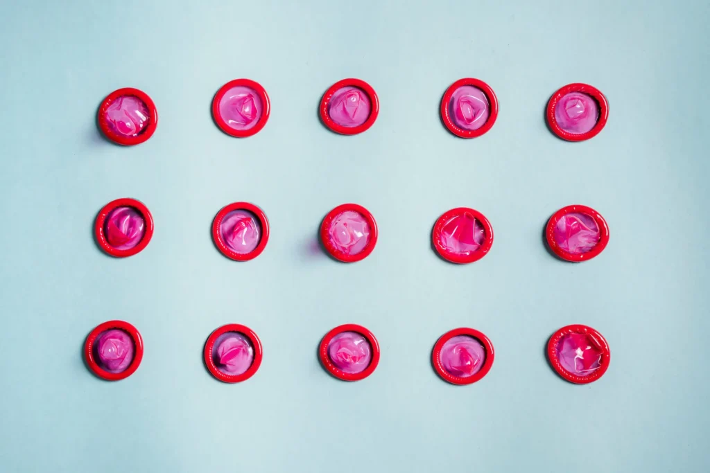 Rows of pink condoms laid out on a light blue background for a condom size chart guide